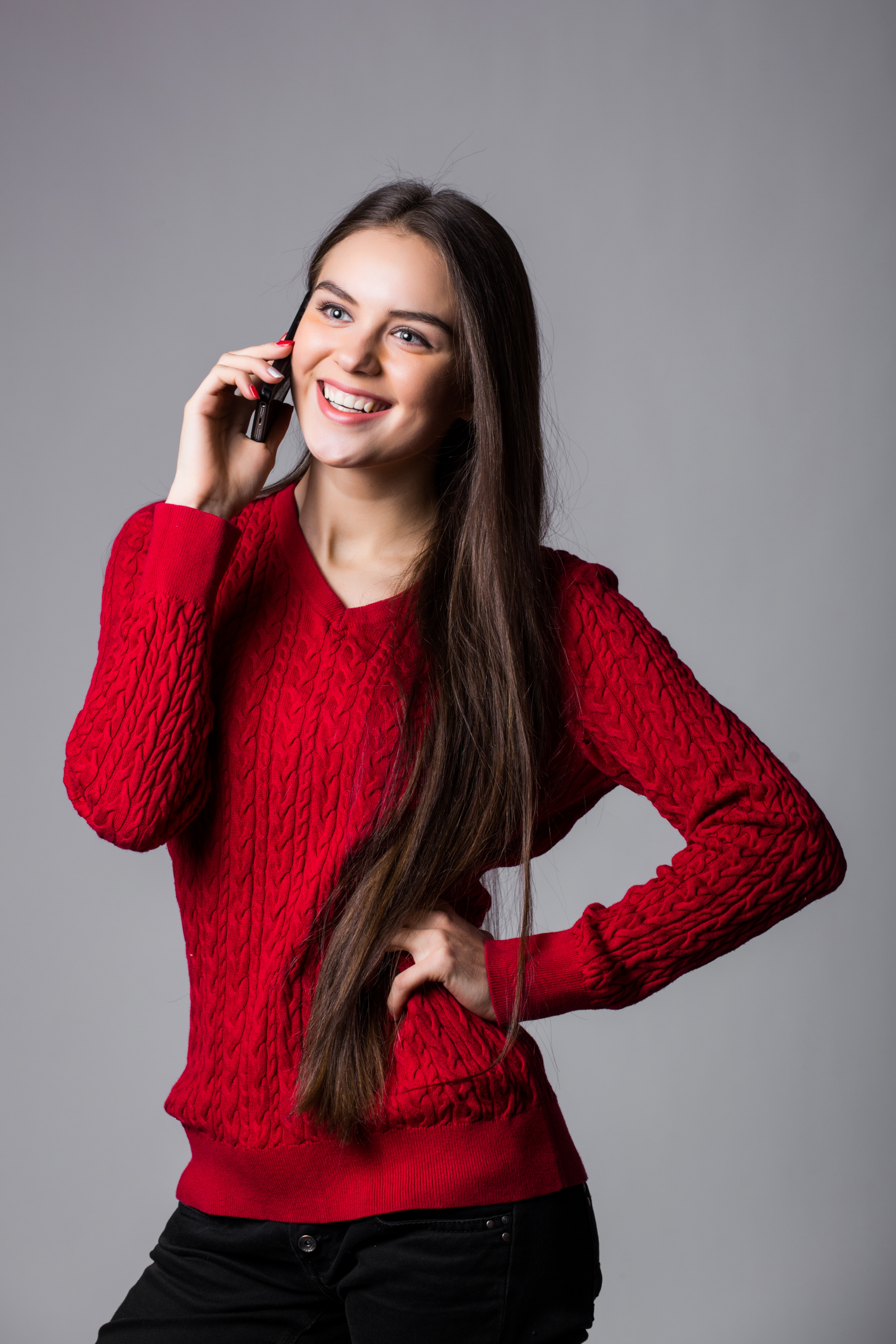 Smiling young woman talking on cell phone over white background